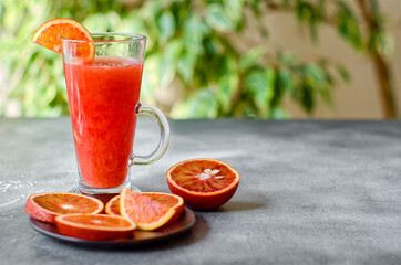 Fresh blood orange juice in a transparent glass on black rough surface