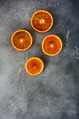 Red blood orange slices on black rough surface. Top view. Space for text