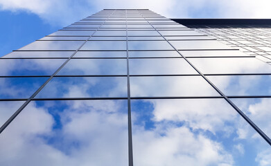 Obraz na płótnie Canvas View of a modern glass skyscraper. Reflection of a cloudy blue sky in a glass skyscraper