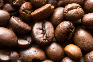 Roasted coffee beans close - up-fragrant background. Brown arabica coffee beans are scattered on the wooden table. Copy space