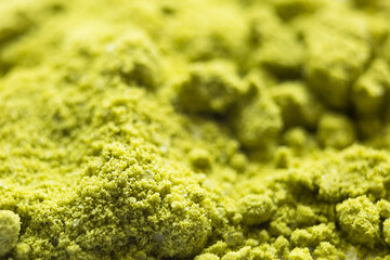 Green powder Japanese matcha tea close-up. The powder contains an admixture of white granules of coconut milk. Matcha latte in dry form. Background, texture