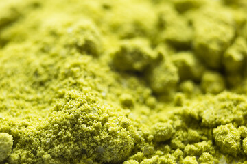 Obraz premium Green powder Japanese matcha tea close-up. The powder contains an admixture of white granules of coconut milk. Matcha latte in dry form. Background, texture