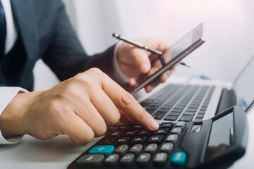 Businesswomen hands working with finances about cost and calculator and laptop with tablet, smartphone at office in morning light