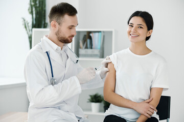 the doctor injects the vaccine into the patient's shoulder hospital and protective gloves infection