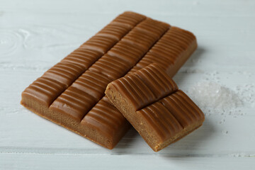 Caramel bar and salt on white wooden background