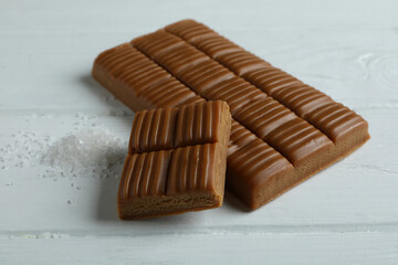 Caramel bar and salt on white wooden background