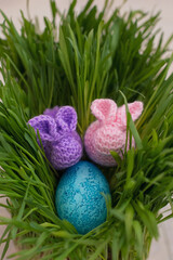 handmade pink and purple  bunnies with egg in green grass, easter