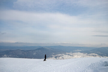 A lone snowboarder riding a snow-covered slope in front of a stunning mountain landscape 