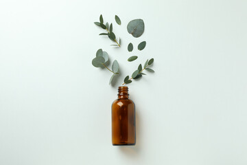 Brown bottle and eucalyptus leaves on white background
