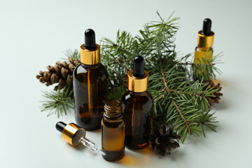 Bottles of pine oil and pine twigs on white background