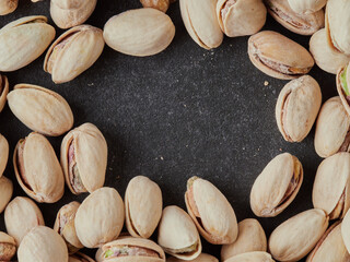 Roasted and fresh pistachios scattered on a black background. View from above. Place for text. Copy space