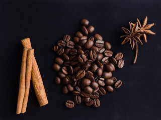 plenty of coffee beans with hot spices for the aroma and taste of the drink on a black background.