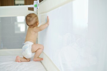 An Asian baby is practicing walking in bed to prevent injury.