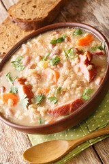 Slovenian barley and bean soup with smoked meat close-up in a bowl on the table. vertical