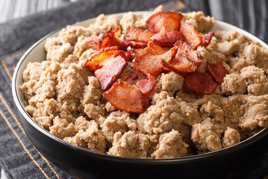 Popular food from Slovenia Ajdovi zganci made from buckwheat flour and fried bacon close-up in a bowl on the table. horizontal