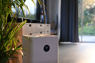 Air purifier with digital monitor screen and house plant in living room for fresh air and healthy...