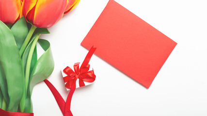 bunch of colorful tulips flowers and gift box with red envelope on white table background. Easter day, Mother day, Valentines day mock up greeting card.