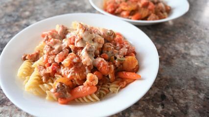 Pasta with vegetables, meet and cheese on wooden table