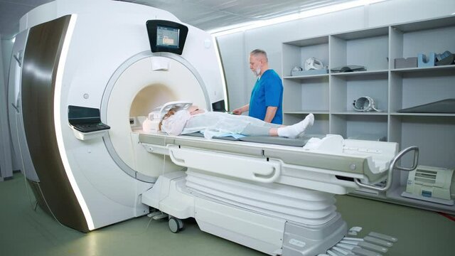 Magnetic resonance imaging in the modern hospital, adult man doctor performs a magnetic tomographic examination of a young woman, MRI, modern technologies in medicine.