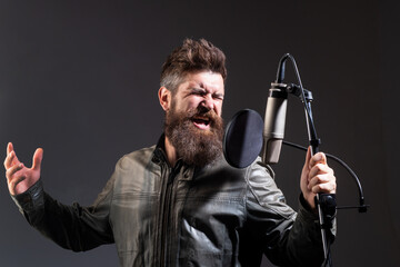 Singer singing rock. Expressive singer with microphone. Sound producer recording song in a music studio. Excited Karaoke.