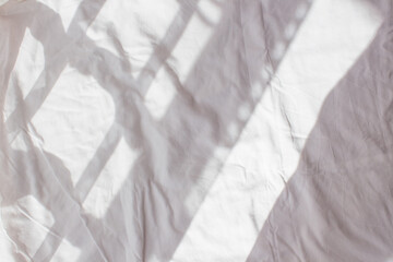  Crumpled white sheet with shadow and light from the window in the morning. The wrinkled background of a straightened bed after the night. White background