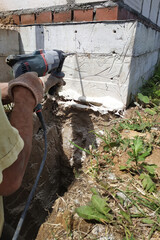 Drilling a hole in the concrete wall with a jackhammer, perforator in operation.