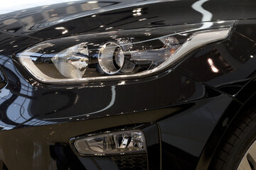 Fototapeta premium New modern unknown car with elegant head lamps. Cropped image. Close up.