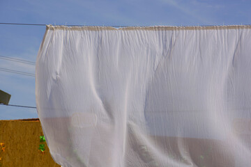 transparent white curtain in the ornamental garden blowes in the summer wind