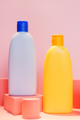 Two plastic cosmetics containers on pink product pedestals. Baby cosmetics products. Shampoo, lotion packaging design mockup.