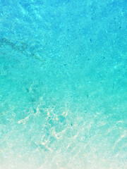 Light blue sea waves on a sandy beach background.