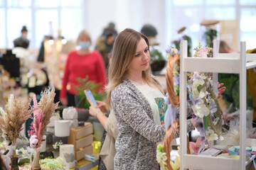 business owner selling behind counter with her bouquet of dried flowers at local market of...
