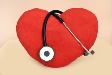 Big red plush heart with stethoscope on the table. Health care and medical concept.  