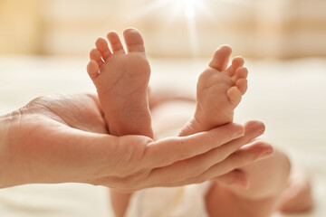 Mother's hand holding newborn baby's barefoot, mommy making massage for infant for normalization of...