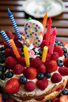 Vibrant candles and number 8 candle on fruit birthday cake
