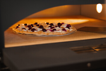 Cook takes the pizza out of oven