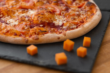 Pizza and cheddar cheese slices on a slate board