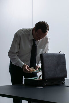 Businessman counting money at briefcase in office
