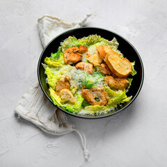 Classic caesar salad with grilled chicken on gray background.