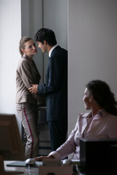 Businessman cornering businesswoman at photocopier in office
