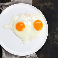 Fried eggs with vegetables on dark grey background