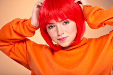Closeup portrait of an young  girl with a red hair over colored background. Pretty teen girl with  freckles on face. Beauty portrait.    Photo of a young fashion model in orange clothes.