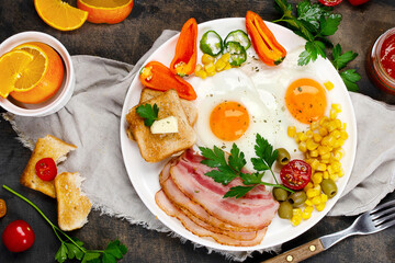 Fried eggs with vegetables on dark grey background