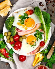 Fried eggs with vegetables on dark grey background