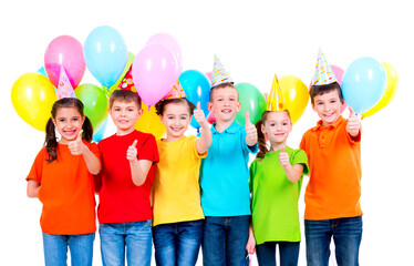 Group of happy children in party hats showing thumbs up sign.