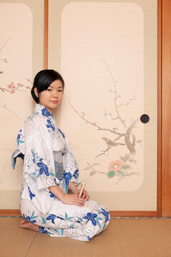 Portrait beautiful young Japanese woman in kimono at painted door
