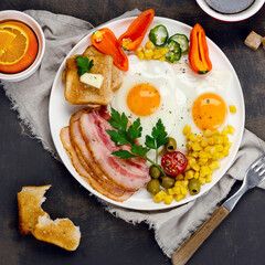 Fried eggs with vegetables on dark grey background
