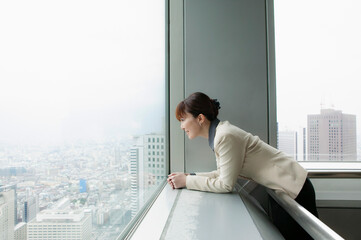 Businesswoman looking out at city view from highrise office
