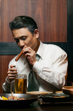 Businessman lighting cigar at restaurant table
