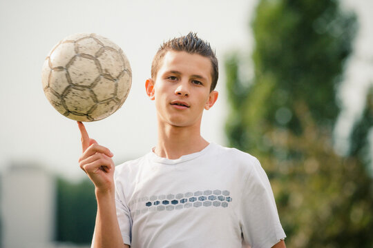 Fototapeta Portrait cool teenage boy spinning soccer ball on finger 