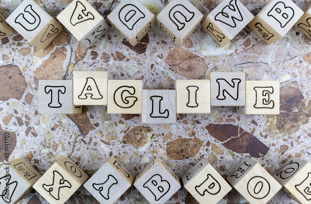 Fototapete Tagline concept with the word on wood blocks and upper and lower borders of wooden cubes with random letters over a marbled stone background